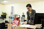 Woman working in office with baby in stroller nearby