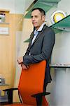 Businessman standing behind office chair, portrait