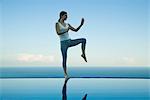 Woman practicing Tai Chi Chuan on edge of infinity pool