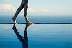 Woman walking along edge of infinity pool, low section