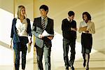 Group of business associates talking as they walk together in lobby