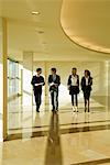 Group of business associates talking as they walk together in lobby