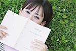 Jeune femme couvrant son visage avec un livre