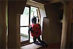 Boy Dressed as Ladybug Sitting on Windowsill