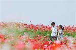 Couple  Walking in Field of Red Flowers