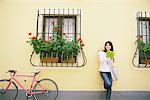 Young Woman  Leaning against Wall and Reading Book