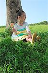 Jeune fille assise dans le parc et manger sucette