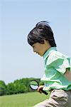 Boy with Magnifying Glass in Park