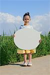 Girl Standing in Park Holding Board