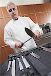 Mid- adult chef sharpens knife
