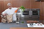 Mid- adult chef lifting carrots into sink