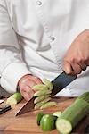 Mid- adult chef slicing cucumber