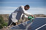 A man on a rooftop working on solar panelling