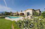 House exterior in daylight with a garden,plants,a swimming pool and hills in the far distance