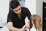 Man cutting and combing a young womans hair in the hairdressers