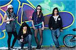 Group of Young Teens Standing in front of Graffiti Covered Wall