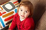 Young girl sitting on sofa looking up