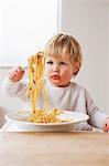 Messy baby boy eating spaghetti