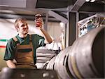 Worker holding pint of beer in brewery