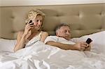 Mature couple in bed using smart phones