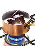 Melting pieces of chocolate in milk in a copper saucepan