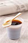 Plastic cup of coffee ,spoon and newspaper