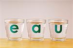 The word "eau" written on three glasses of water