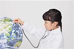 Girl with Stethoscope Listening To Globe