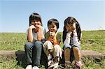 Children Sitting In Grassy Field