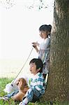 Girl and Boy with Poodle Dog near Tree Trunk