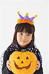 Girl Dressed in Halloween Costume Holding Pumpkin