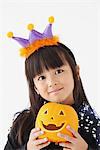 Girl Dressed in Halloween Costume Holding Pumpkin