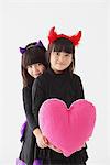 Two Girls In Halloween Costume Holding Heart