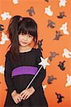 Jeune fille habillée en Costume pour Halloween tenant la baguette magique