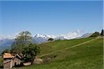France, Hautes-Alpes, Gap.  High altitude shepherds barn with snow covered peaks of the Alps in the background.