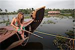 India, Kerala. Young girl fishing from a houseboat in the Kerala Backwaters.