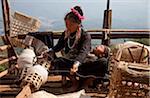 Myanmar, Burma, Keng Tung (Kyaing Tong). An Ann (Enn) lady spinning thread on the platform of her home, with her sleeping baby on her lap, Paunglea village, Keng Tung.