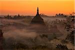 Myanmar, Burma, Mrauk U. Evening mist and smoke from village cooking fires swirl around Ratanabon Paya, Mrauk U, Rakhine State.