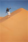 Oman, Empty Quarter. A young lady makes her way up the steep dunes.