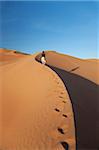 Oman, vide. Une jeune femme fait son chemin jusqu'à les dunes abruptes.