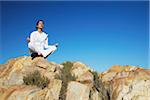 Woman practicing yoga on rocks, Plettenberg Bay, Western Cape, South Africa