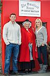 UK, North Wales; Conwy. Couple stand outside The Smallest House in Britain with a lady in traditional Welsh dress.