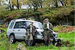 North Wales, Snowdonia ; Gilar Farm. A man and woman relax leaning against their landrover whilst out shooting.