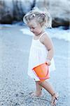 Kleines Mädchen mit Eimer am Strand