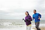 Couple en cours d'exécution sur la plage les jours nuageux