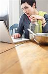 Woman looking at laptop whilst cooking