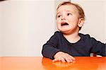 Little boy sitting on table crying