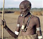 An old Dassanech man wearing a traditional metal lip ornament and metal earrings. His broad ivory armbands and his ivory tobacco container hanging round his neck, are uncommon because elephants no longer frequent the Omo Delta.The Dassanech people live in the Omo Delta of southwest Ethiopia, one of the largest inland deltas in the world.