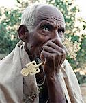 Profondément dans la pensée, un vieil homme avec croix orthodoxe en main repose en dehors de la roc taillé église de Abune Yemata dans les montagnes de Gheralta près Guh.Abune Yemata est atteint que par une montée dangereuse avec petits échelons et poignées irrégulières.