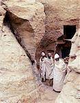 Priests of the Ethiopian Orthodox Church pause at the entrance to the rock hewn church of Yohannes Maequddi, a two hour walk from Degum on a plateau of the Gheralta Mountains east of Debretsion.The access to the church is along a narrow cleft between glaring sandstone.